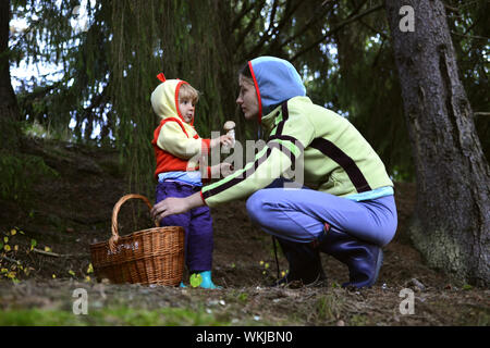 Eine Mutter und ihre kleine Tochter Pilze im Wald im bascket, Anzeigen, Stockfoto