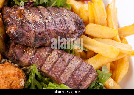 Gesunde platter gemischter Aufschnitt einschließlich gegrilltes Steak, knusprig panierte Hähnchen und Rindfleisch auf einem Bett von frischem grünem Salat serviert mit Französischen Stockfoto