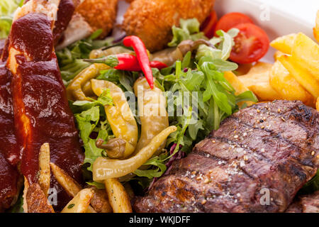 Gesunde platter gemischter Aufschnitt einschließlich gegrilltes Steak, knusprig panierte Hähnchen und Rindfleisch auf einem Bett von frischem grünem Salat serviert mit Französischen Stockfoto