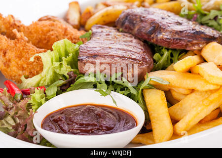 Gesunde platter gemischter Aufschnitt einschließlich gegrilltes Steak, knusprig panierte Hähnchen und Rindfleisch auf einem Bett von frischem grünem Salat serviert mit Französischen Stockfoto