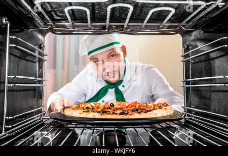 Chefkoch Pizza in den Ofen, Blick aus dem Inneren des Ofens. Kochen in den Ofen. Stockfoto