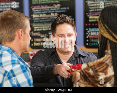 Lächelnde Hispanic Kaffeehaus Eigentümer servieren Getränke Stockfoto