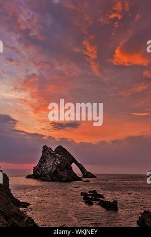 Bogen GEIGE ROCK PORTKNOCKIE Küste von Moray in Schottland eine frühe bunten Sommer SONNENAUFGANG mit Orange und Lila Wolken Stockfoto