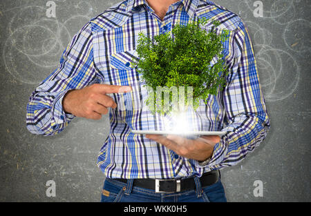 Mann Tablet-PC mit grünen Bäumen und hellem Licht. Eco-Konzept Stockfoto