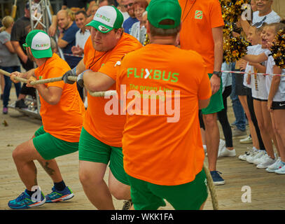 Wolfsburg, Deutschland, September 1., 2019: Das Team der starken Männer aus Flixbus ist Ziehen an einem dicken Seil bei einer öffentlichen Veranstaltung. Stockfoto