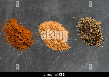 Drei verschiedene bunte Pulver Gewürze kleine Stapel auf schwarze Tafel Hintergrund. Stockfoto