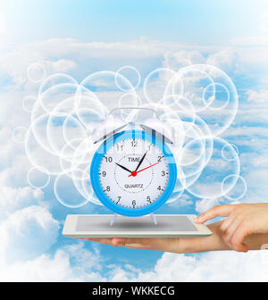 Händen halten Tablet-PC mit Wecker. Blauer Himmel Stockfoto