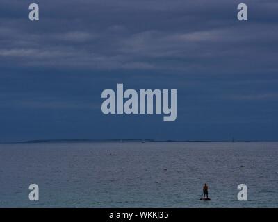 Stand Up Paddle dans l'océan en face de la plage de Brest avec une Île de fond, ciel Couvert Stockfoto