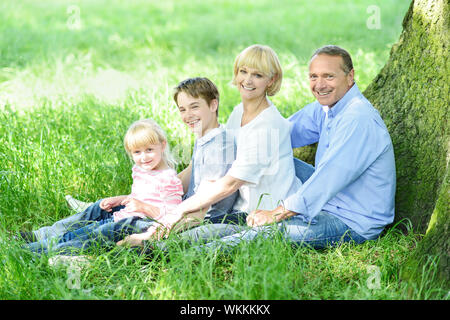 Jovial Familie ruht unter einem Baum im Schatten Stockfoto