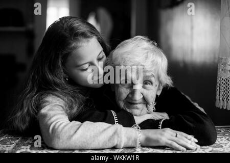 Portrait von eine ältere grauhaarige Frau mit ihrem geliebten Enkelin. Schwarz-weiß Foto. Stockfoto