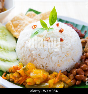 Nasi Lemak Kukus traditionelle malaysische würziges Reisgericht. Serviert mit Belacan, Ikan Bilis, Acar, Erdnüssen und Gurken. Stockfoto