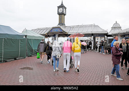 Hintere zurück Blick auf Familie zu Fuß zu Brighton Pier tragen Regenjacke und Regenschirm im August Sommer East Sussex England UK KATHY DEWITT Stockfoto