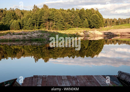 Zone Rest. Blaue Wasser in einem See mit Pinien. Der Wald spiegelt sich im Wasser. Weißrussland Stockfoto