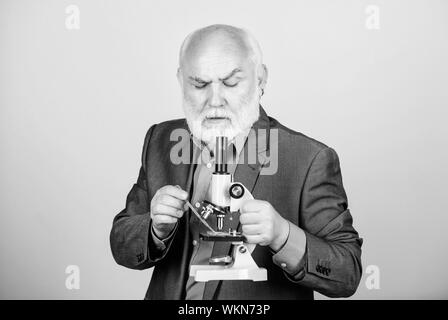 Reifer mann Anzug mit Mikroskop. Promotion und Habilitation die Beschäftigung. Molekularbiologie PhD Projekte. Biologie erfahrene Dozentin. Professor Dozent. Wissenschaftler der Mikrobiologie. Stockfoto