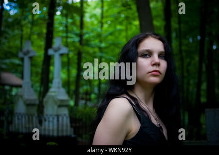 Gothic Girl walking durch Friedhof Kreuze auf Hintergrund Stockfoto