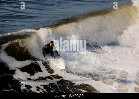 Surfer aufsteht auf einer Welle. Die Welle dreht sich mit Schaum und Spritzer. Stockfoto