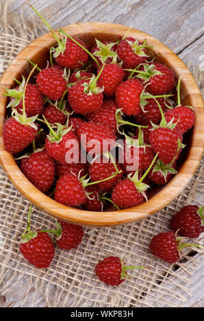 Perfekte Reife Himbeeren mit Stängel in Houten auf Sack und Holz- Hintergrund. Ansicht von oben Stockfoto