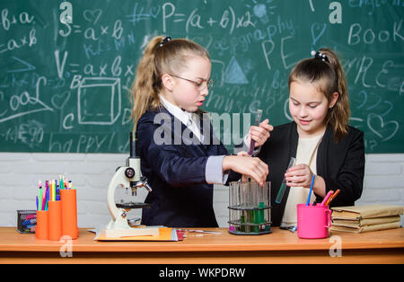 Grundkenntnisse der Chemie. Schüler nette Mädchen Röhrchen mit Flüssigkeiten verwenden. Chemisches experiment Konzept. Sicherheitsmaßnahmen für die sichere chemische Reaktion. Genius Kinder arbeiten an eigenen chemischen Theorie. Stockfoto