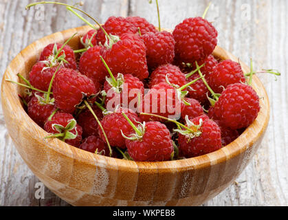 Perfekte Reife Himbeeren mit Stängel in Houten closeup auf rustikalen Holzmöbeln Hintergrund Stockfoto