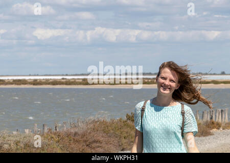 Tausendjährige blonde Mädchen zu Fuß auf der Straße in der Camargue durch Salzwasser Lagunen in der Camarque regionaler Naturpark, Provence Alpes Côte d'Azur, Frankreich Stockfoto