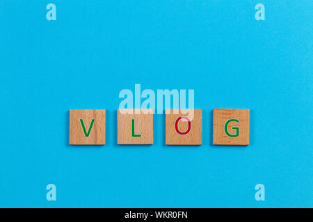 Das Wort VLOG, Dinkel mit hölzernen Buchstabensteine über blauen Hintergrund. Ansicht von oben Stockfoto