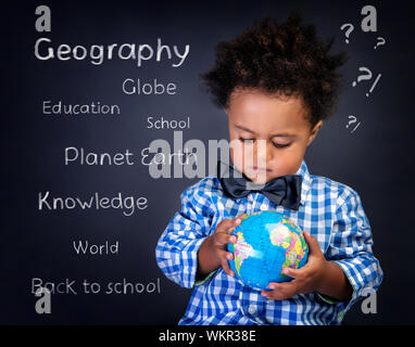 Closeup Portrait von niedlichen kleinen afrikanischen jungen mit kleinen Globus in Händen, Erdkundeunterricht, zurück zum Schulkonzept wird vorbereitet Stockfoto