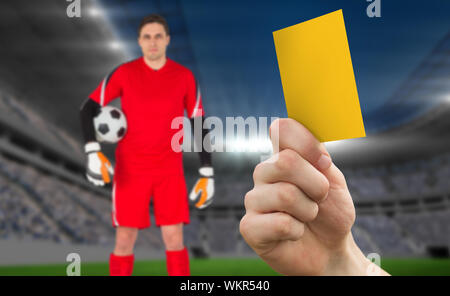 Hand bis gelbe Karte gegen Fußball Stadion mit Goalie Stockfoto