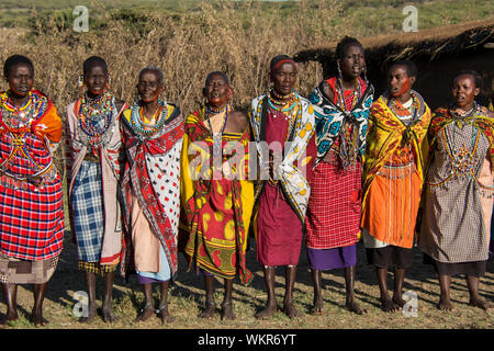 Gruppe von Massai Frauen tragen traditionelle Kangas, Dorf in der Nähe der Masai Mara, Kenia, Ostafrika Stockfoto