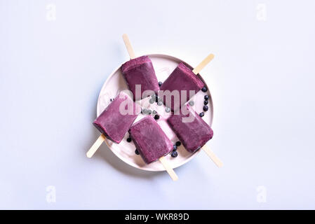 Heidelbeere Eis am Stiel auf blauen Stein Hintergrund mit freiem Speicherplatz. Kalten Sommer Nachtisch. Ansicht von oben, flach Stockfoto