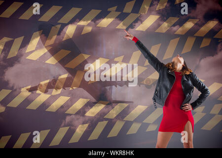 Das zusammengesetzte Bild im brunette im roten Kleid und Biker Jacket gegen Warnband Stockfoto