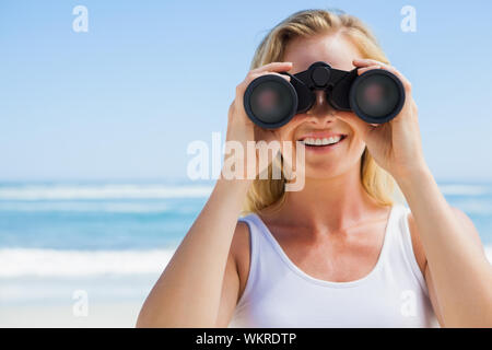 Blonde Blick durch ein Fernglas am Strand an einem sonnigen Tag Stockfoto