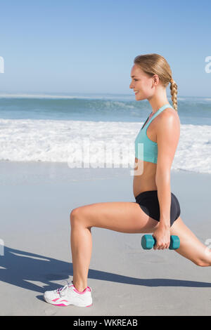 Passende Frau tun gewichteten lunges am Strand an einem sonnigen Tag Stockfoto