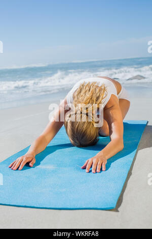 Wunderschöne passen Blonde in embryostellung am Strand an einem sonnigen Tag Stockfoto