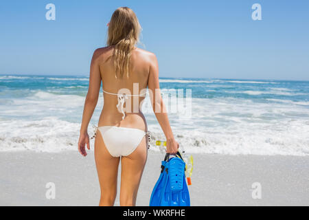 Passende Frau in weißen Bikini holding Schnorcheln am Strand an einem sonnigen Tag Stockfoto