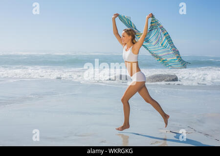 Wunderschöne passen Blonde läuft am Meer mit Schal an einem sonnigen Tag Stockfoto