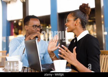 Schwarze Afrikanische amerikanische Kollegen tun digitale Teamarbeit rund um eine Tasse Kaffee Stockfoto