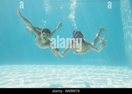 Nettes Paar unter Wasser im Pool mit Schnorchel und Seesterne für Ihren Urlaub Stockfoto