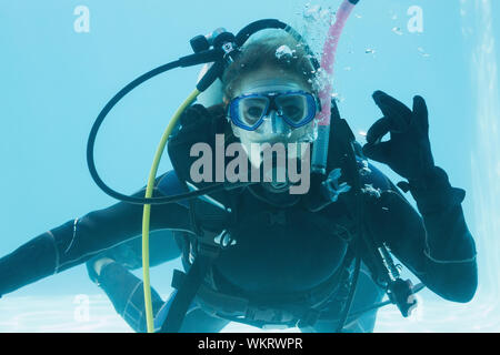 Frau auf scuba Training im Schwimmbad machen ok Zeichen auf Ihrem Urlaub unter Wasser Stockfoto