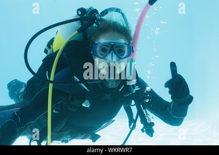 Frau auf scuba Training im Schwimmbad Daumen oben auf ihr Urlaub unter Wasser Stockfoto