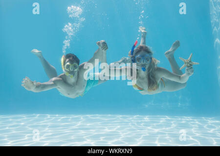 Nettes Paar unter Wasser im Pool mit Schnorchel und Seesterne für Ihren Urlaub Stockfoto