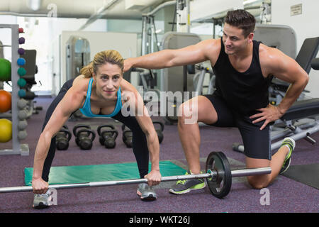 Personal trainer Coaching weibliche Bodybuilder anheben Barbell in der Turnhalle Stockfoto