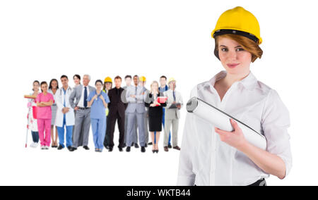 Das zusammengesetzte Bild von der hübschen jungen Architekten an Kamera lächelnd gegen die Gruppe der Arbeitnehmer Stockfoto