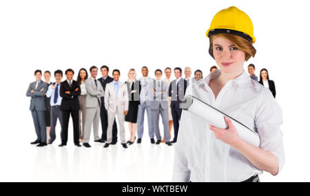 Das zusammengesetzte Bild von der hübschen jungen Architekten an Kamera lächelnd gegen die Gruppe der Arbeitnehmer Stockfoto