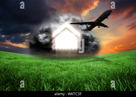 Haus in graue Wolke mit dem Flugzeug gegen grüne Feld unter orange sky