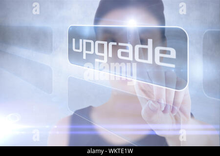 Geschäftsfrau, die auf Word Upgrade gegen graue Wand Stockfoto