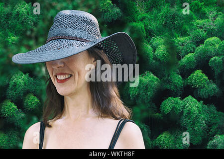 Frau mit schwarzen Pamela lächelnd vor einem Bambus Garten II, Spanien - Europa Stockfoto