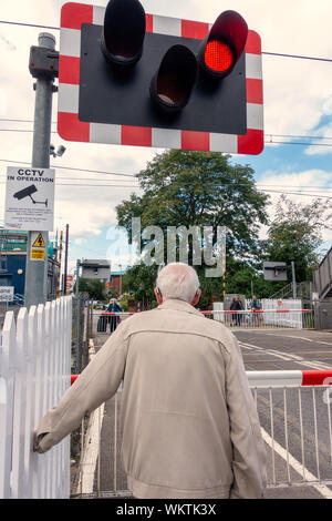 Nahaufnahme Rückansicht ein grauhaariger alter Mann am Bahnhof warten Kreuzung Stockfoto