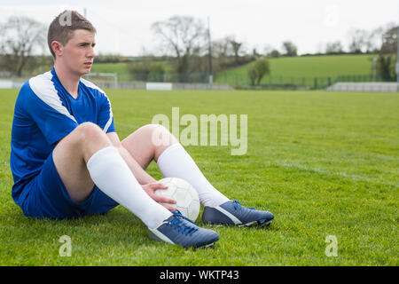 Fußball-Player in blau eine Pause auf dem Platz an einem klaren Tag Stockfoto