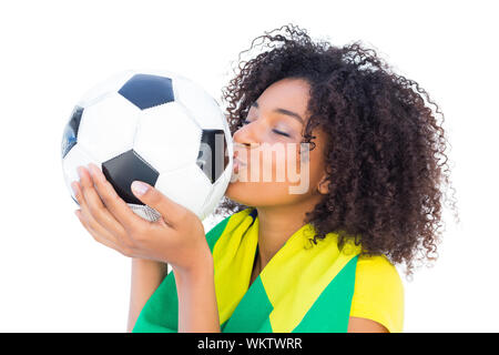 Ziemlich Fußball-Fan mit brasilianischer Flagge küssen Ball auf weißem Hintergrund Stockfoto
