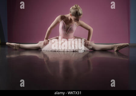 Anmutige ballerina Sitzen mit ausgestreckten Beinen im Ballett studio gestreckt Stockfoto